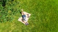 Young woman using laptop computer in park, student girl sitting on grass with headphones and laptop, aerial drone view Royalty Free Stock Photo