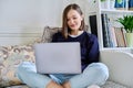 Young woman using laptop sitting on sofa at home Royalty Free Stock Photo