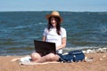 Young woman using laptop computer on sunbed on a beach. Freelance work concept, Freelancer outside Royalty Free Stock Photo