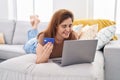 Young woman using laptop and credit card lying on sofa at home Royalty Free Stock Photo