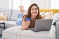 Young woman using laptop and credit card lying on sofa at home Royalty Free Stock Photo