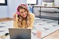 Young woman using laptop and headphones lying on floor at home Royalty Free Stock Photo