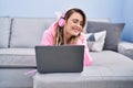 Young woman using laptop and headphones lying on sofa at home Royalty Free Stock Photo