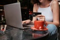 Young Woman Using Laptop and Holding Credit Card While Sitting in a Cafe Outdoors, Online Shopping Concept Royalty Free Stock Photo