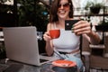 Young Woman Using Laptop and Holding Credit Card While Sitting in a Cafe Outdoors, Online Shopping Concept Royalty Free Stock Photo