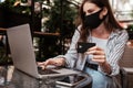 Young Woman Using Laptop and Holding Credit Card While Sitting in a Cafe Outdoors, Online Shopping Concept Royalty Free Stock Photo