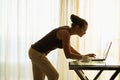 Young woman using laptop leaning against table Royalty Free Stock Photo