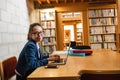 Young woman using laptop in library Royalty Free Stock Photo