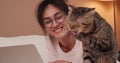 Young woman using laptop and look cat on bed.