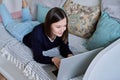 Young woman using laptop lying on sofa at home Royalty Free Stock Photo