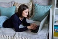 Young woman using laptop lying on sofa at home Royalty Free Stock Photo