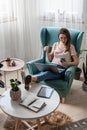 Young woman using laptop, mobile phone, drinking coffee, multiple devices