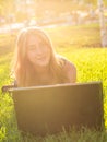 Young woman using laptop in the park lying on the green grass. Leisure time activity concept Royalty Free Stock Photo