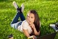 Young woman using laptop in the park lying on the green grass. Leisure time activity concept. Royalty Free Stock Photo