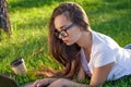 Young woman using laptop in the park lying on the green grass. Leisure time activity concept. Royalty Free Stock Photo