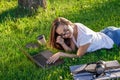 Young woman using laptop in the park lying on the green grass. Leisure time activity concept. Royalty Free Stock Photo