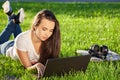 Young woman using laptop in the park lying on the green grass. Leisure time activity concept. Royalty Free Stock Photo