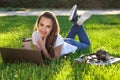 Young woman using laptop in the park lying on the green grass. Leisure time activity concept. Royalty Free Stock Photo