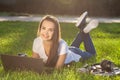 Young woman using laptop in the park lying on the green grass. Leisure time activity concept. Royalty Free Stock Photo