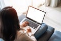 Young woman using laptop and relaxing on sofa in living room at cozy home in the morning Royalty Free Stock Photo