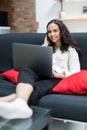 Young pretty woman using laptop while sitting on comfortable sofa, home interior Royalty Free Stock Photo
