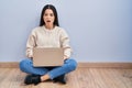 Young woman using laptop sitting on the floor at home afraid and shocked with surprise and amazed expression, fear and excited Royalty Free Stock Photo