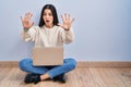 Young woman using laptop sitting on the floor at home doing stop gesture with hands palms, angry and frustration expression Royalty Free Stock Photo