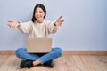 Young woman using laptop sitting on the floor at home looking at the camera smiling with open arms for hug Royalty Free Stock Photo