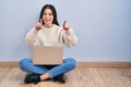 Young woman using laptop sitting on the floor at home pointing to you and the camera with fingers, smiling positive and cheerful Royalty Free Stock Photo