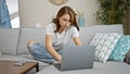 Young woman using laptop sitting on sofa at home Royalty Free Stock Photo