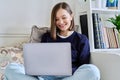 Young woman using laptop sitting on sofa at home Royalty Free Stock Photo