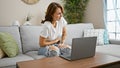 Young woman using laptop sitting on sofa suffering for stomachache at home Royalty Free Stock Photo