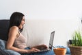 Young woman using laptop on sofa - Happy girl having fun in computer video call at home Royalty Free Stock Photo