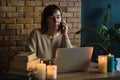 Young woman using laptop to work at home during electricity outage. Remote work at home concept. Woman speaking on the phone