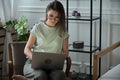Young woman using laptop, typing, sitting in a chair, remote work, work at home Royalty Free Stock Photo