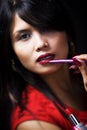 Young woman using lipstick brush