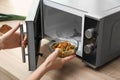 Young woman using microwave oven on table