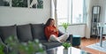 Young woman using mobile cell phone sitting on couch in living room. Royalty Free Stock Photo