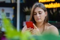 Young woman using mobile phone, communication, looking at digital screen, sitting in street cafe Royalty Free Stock Photo