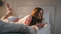Young woman using mobile phone at home. Smiling happy female lying in bed typing Royalty Free Stock Photo
