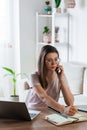 Young woman using mobile phone and laptop to work home, remote work Royalty Free Stock Photo