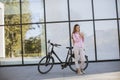 Young woman using mobile phone by modern city electric e-bike as clean sustainable urban transportation