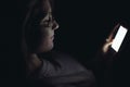 Young woman using mobile phone at night in darkness