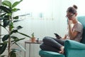 Young woman using mobile phone while sitting in cozy armchair