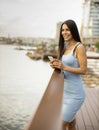 Young woman using a mobile phone while standing on the river promenade Royalty Free Stock Photo