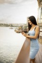 Young woman using a mobile phone while standing on the river promenade Royalty Free Stock Photo