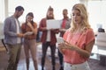 Young woman using mobile phone with team working in background Royalty Free Stock Photo