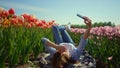 Young woman using mobile phone at walk in beautiful blooming park in sunny day. Royalty Free Stock Photo