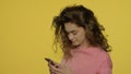 Young woman using mobile phone on yellow. Woman typing message on mobile phone Royalty Free Stock Photo