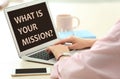 Young woman using modern laptop with question WHAT IS YOUR MISSION? on screen, closeup Royalty Free Stock Photo